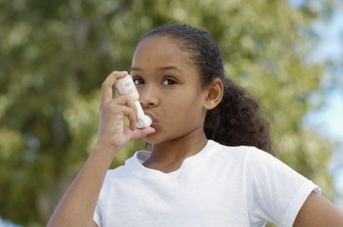 A girl using her metered-does asthma inhaler