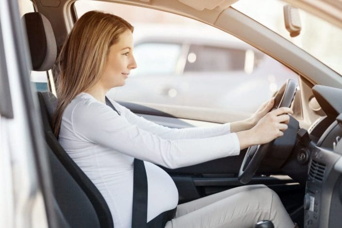 pregnant woman driving her car, wearing seat belt