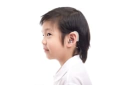 young Asian boy with hearing device in ear