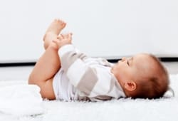 an infant lies on her back without a diaper