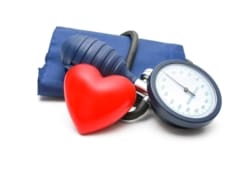 Blood pressure cuff and meter with a small, red heart positioned in front