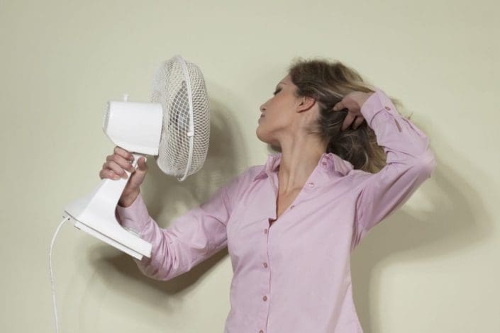 A woman trying to cool herself with a tabletop fan