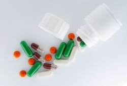 A variety of colorful pills and capsules spilling from a medicine bottle