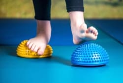 Girl walking over balancing pods during physical therapy for flat feet