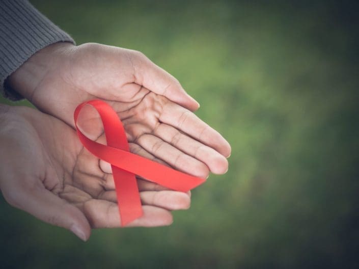 hands holding a red ribbon for HIV awareness