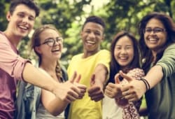 group of teenagers laughing and giving thumbs up in a park