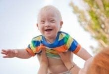 Portrait of a baby with Down syndrome. A mother picking up her son, the child is happy and flying up