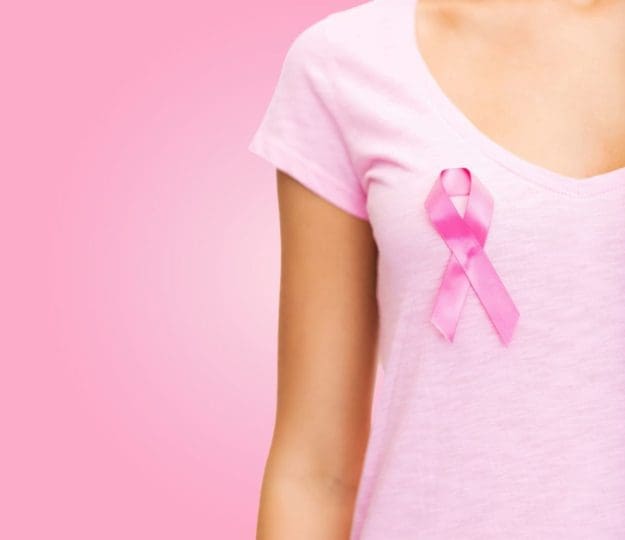 A woman dressed in pink wears a pink ribbon on her chest to promote breast cancer awareness. Breast cancer is the second most common cancer among women, but its death rate has declined over the last few years thanks to early detection.