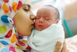 mother holds and kisses her newborn baby