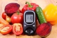 A glucose meter propped up among a tabletop of fruit and vegetables