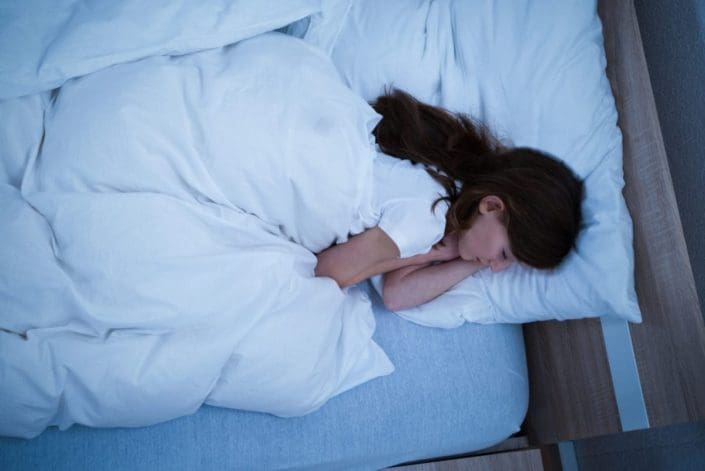 young girl sleeping on cozy bed with white blanket