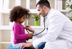 Doctor listens to young girl’s heartbeat