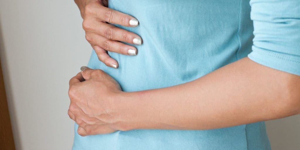 Woman with gallstones holds her stomach in pain