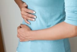 Woman with gallstones holds her stomach in pain