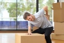 Man suffering from backache while moving boxes