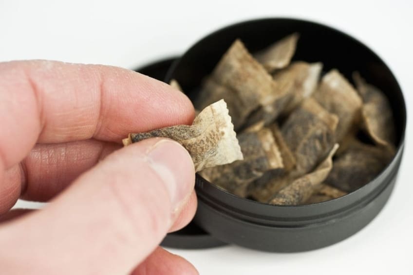 A hand grabbing a pinch of snuff