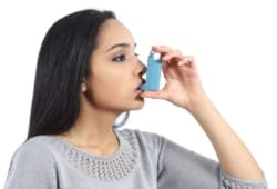 A woman breathing from an inhaler