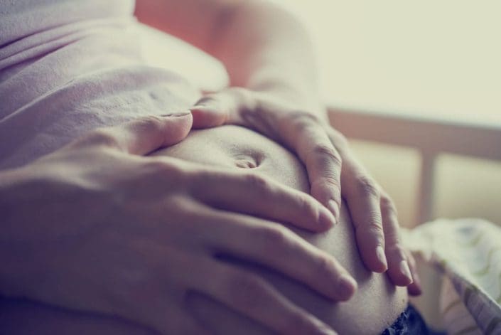 close-up of pregnant woman with her hands on her stomach