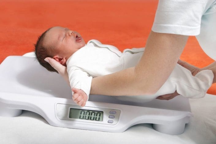 a newborn baby being placed on a scale