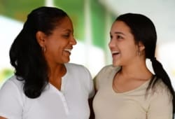 mother and daughter embrace and smile at each other