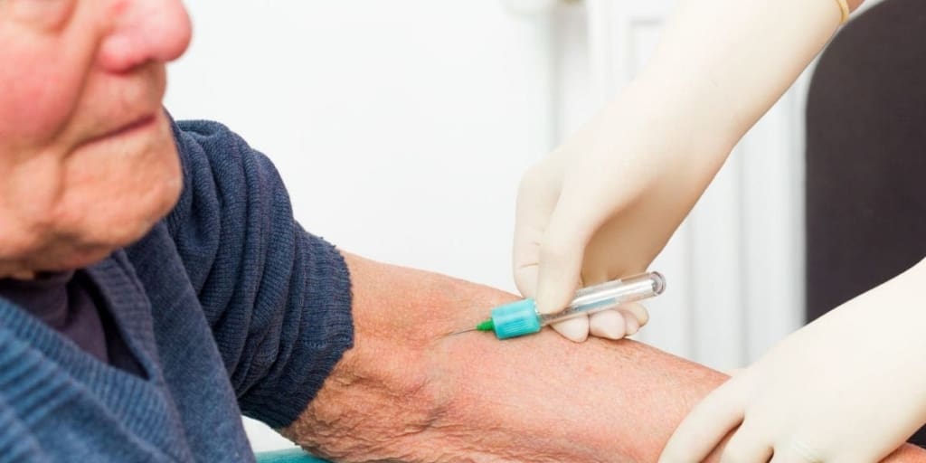senior man receives injection from medical worker with gloved hands