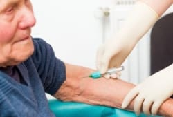 senior man receives injection from medical worker with gloved hands