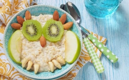 kids breakfast of oatmeal layered with fruit and nuts so it looks like an owl