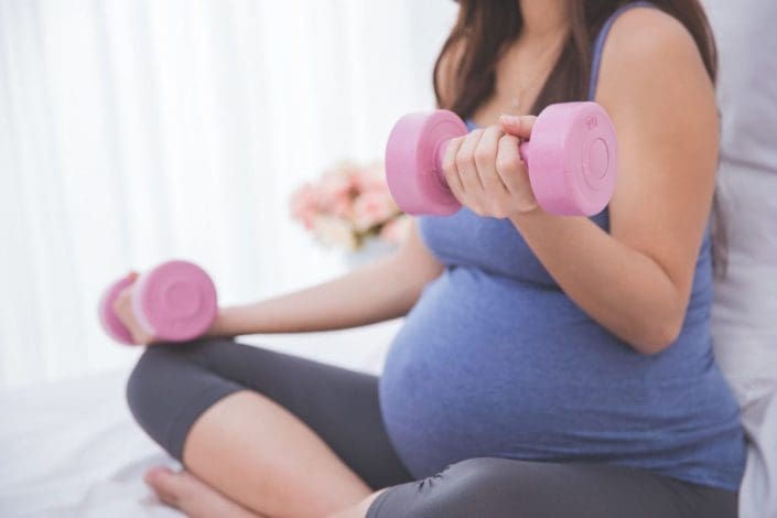 Pregnant woman uses dumbbells to exercise