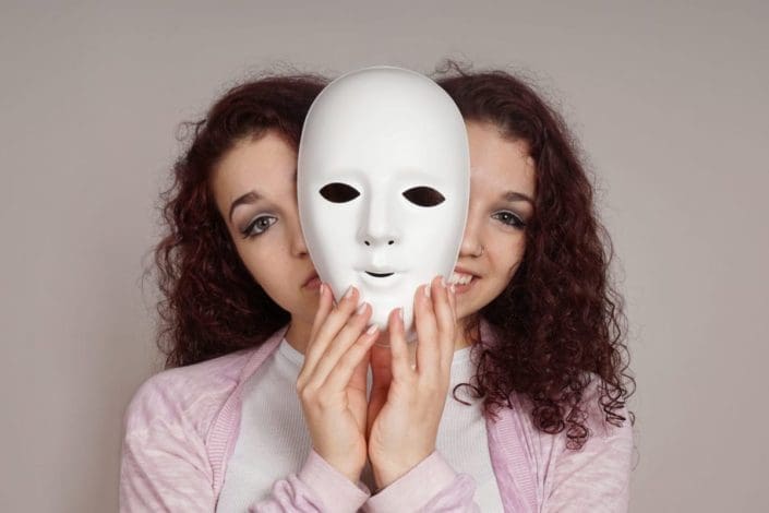 Two-faced woman, one happy and one sad, holding neutral mask in between