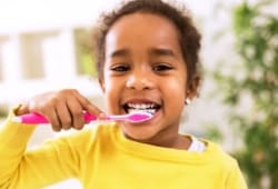 Little girl brushing her teeth and smiling