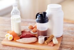Lots of healthy proteins and protein drinks sitting on a wooden cutting board