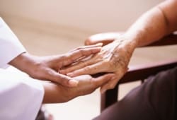Touching hands of ill patient in hospice care and doctor providing care