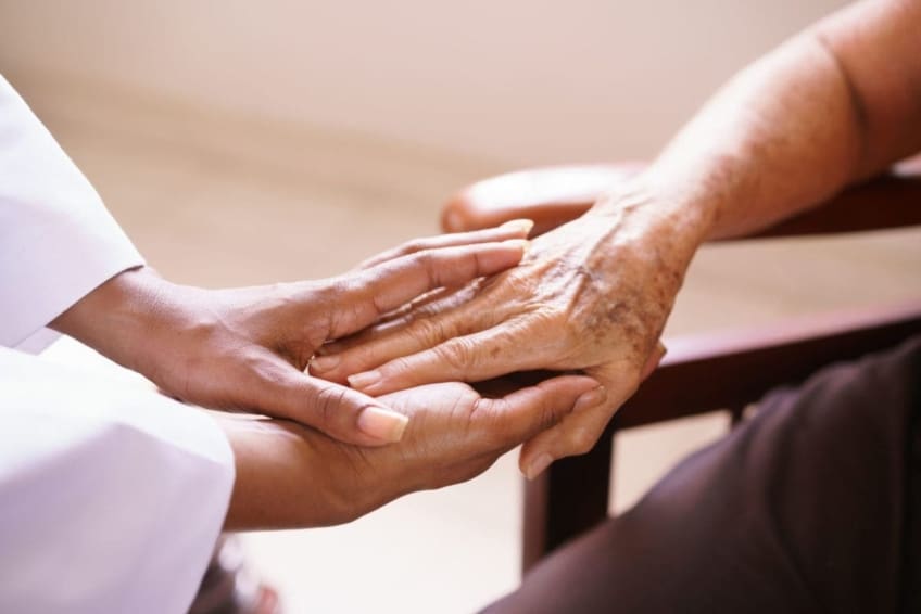 Touching hands of ill patient in hospice care and doctor providing care