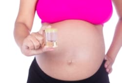 A pregnant woman holding a urine sample