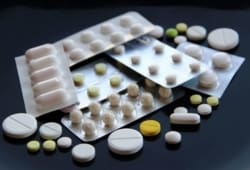 Sealed tablets packs and scattered pills on black surface