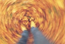 blurred, spinning picture of a person’s feet as they walk through fall leaves