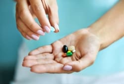 closeup of female hand holding variety of colorful pills on palm