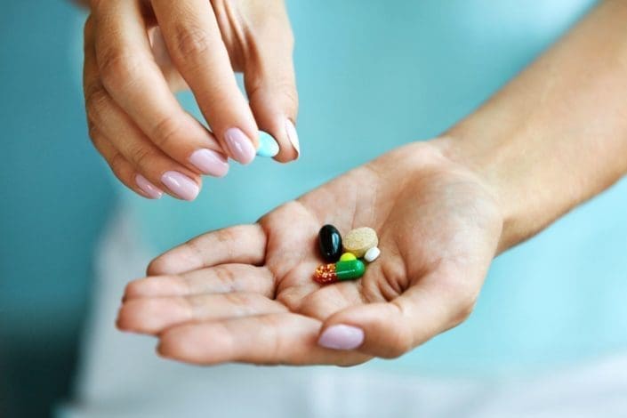 closeup of female hand holding variety of colorful pills on palm