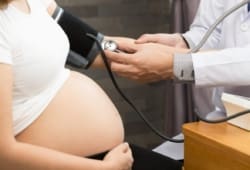 doctor checks blood pressure of a pregnant woman