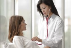 doctor using stethoscope to listen to woman’s heart