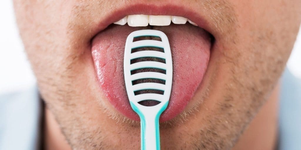 A man scraping his tongue with a tongue scraper