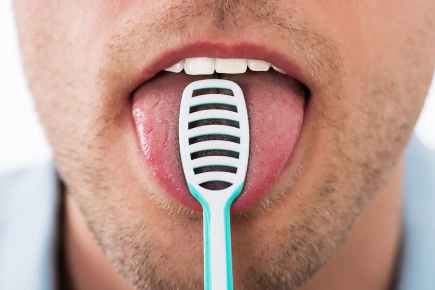 A man scraping his tongue with a tongue scraper