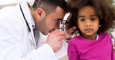 A doctor using a otoscope to look inside a young girls ear canal