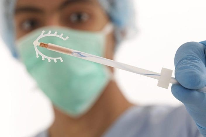 Young doctor holding an IUD, which is used for birth control