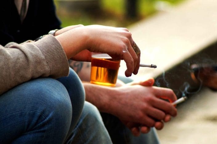 Hands holding beer and a cigarette