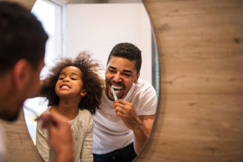 A father and daughter brushing their teeth together