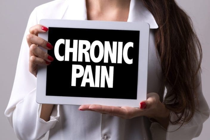 A woman holding a sign that reads, “Chronic Pain”