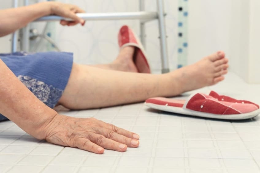 Senior person sitting on floor next to walker