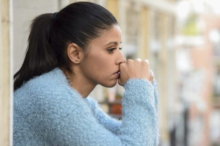 Sad, young woman staring off a balcony