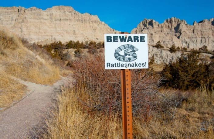 Beware of rattlesnakes sign in front of mountains